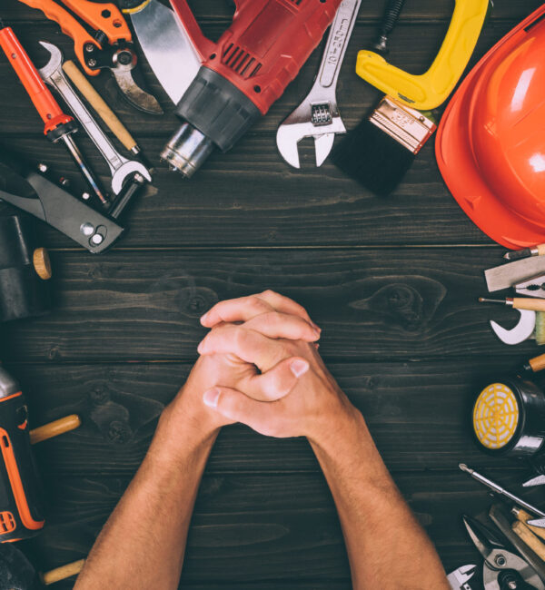 partial view of hands in lock and carpentry equipment around on wooden surface